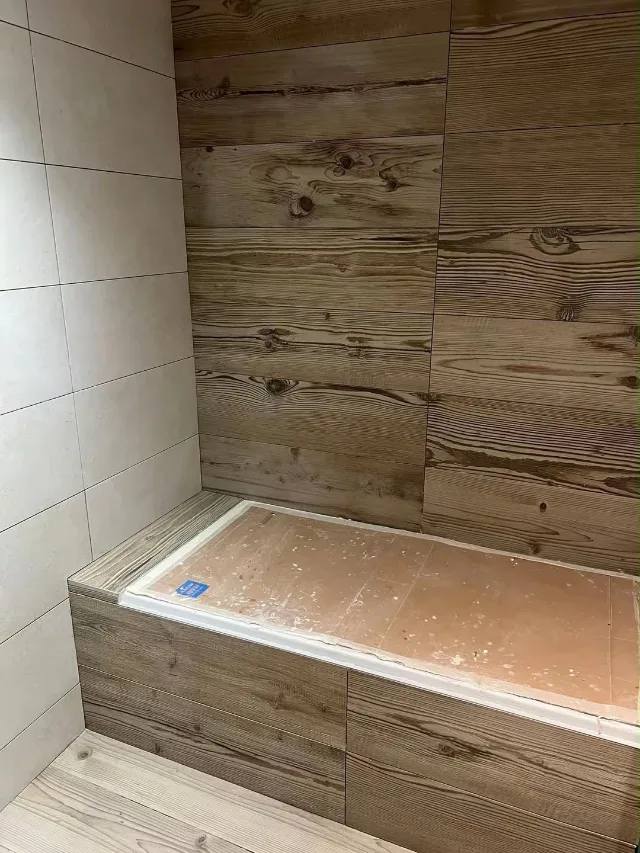 Habillage bois d'une baignoire encastrée et sa jonction avec la faïence.