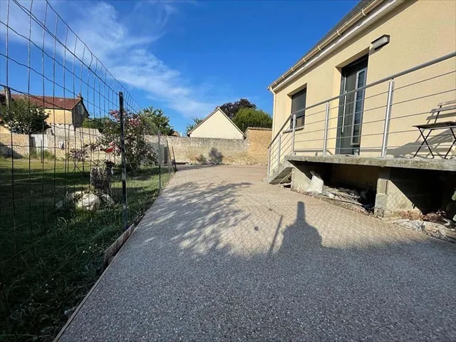 Allée en béton désactivé le long d'une maison, avec garde-corps et bordure.