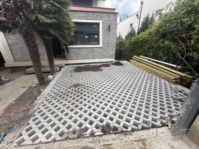 Stationnement en dalles alvéolées posées sur lit de gravier, en pied de maison.