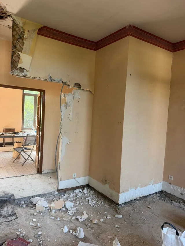 Pièce en cours de dépose : cloison ouverte, plafond déposé, gravats au sol.