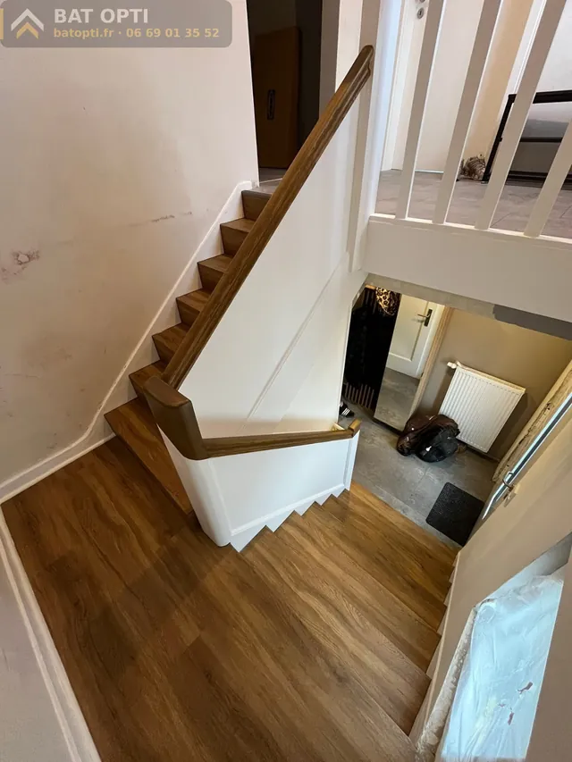 Escalier habillé effet bois vu d'en haut, palier assorti, main courante bois.
