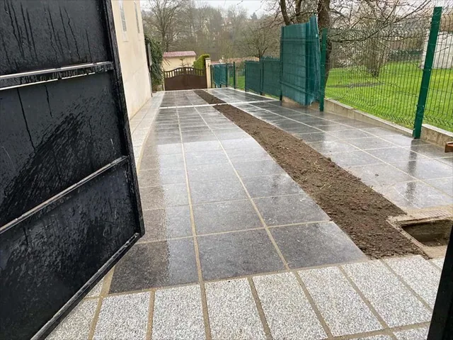 Terrasse carrelée à deux tons avec bande de terre en attente de plantation.
