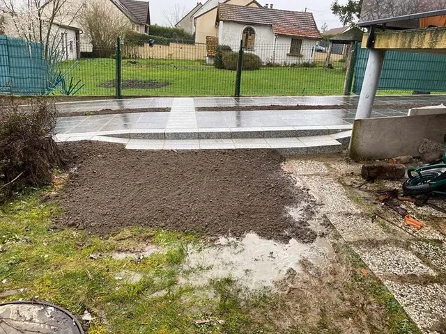 Terrasse en carrelage gris grand format, bordure claire, jardin clos à l'arrière.
